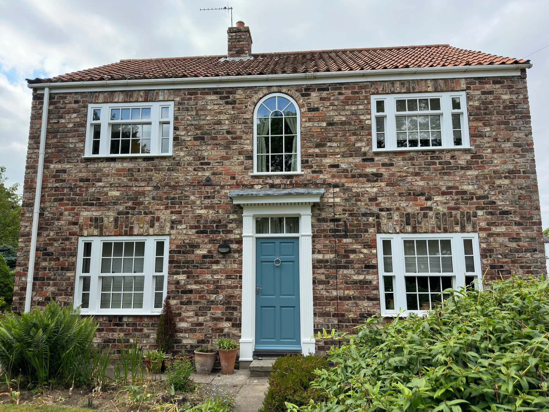 Traditional brick home with white windows and a blue entrance door